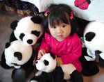 A young girl surrounded by stuffed pandas.